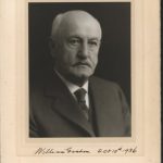 Portrait of William Graham in 1936. He is wearing a suit jacket, white shirt and tie. He is balding and sports a manicured moustache.