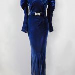 Royal blue velvet dress, long sleeves and skirt touches the ground. There is a silver buckle at the waist.