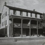 Large three-story building with second floor veranda and six windows facing the road on the third level.